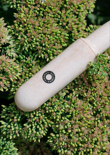 White cylindrical object with a brand logo on a green plant background